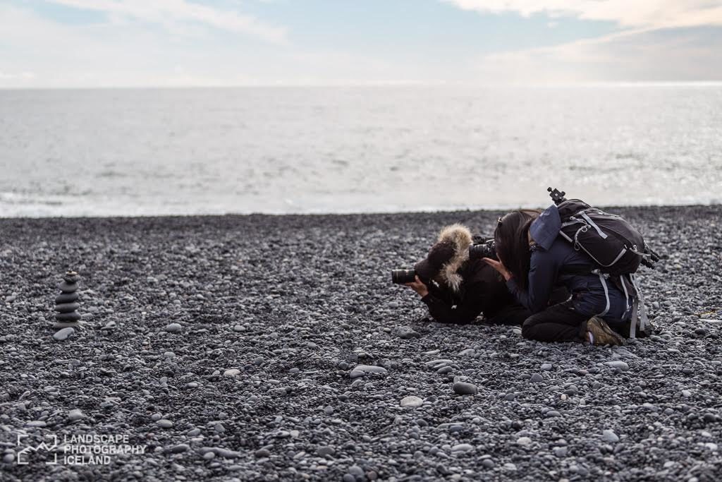 bending down to take photo of rocks on the black beach