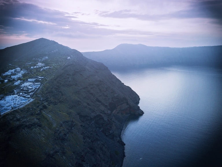 Mountain and lake landscape at dusk with cloudy sky.