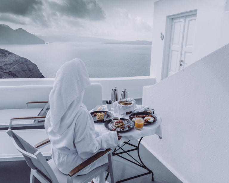 Sea view breakfast in Santorini with traditional Greek pastries and fresh orange juice.